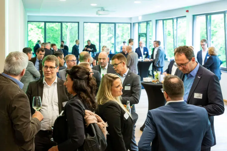 Eine Gruppe von Menschen unterhält sich bei einer Netzwerkveranstaltung in einem Konferenzraum.