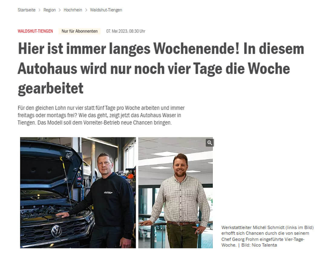 Zwei Männer stehen in einem Autohaus neben einem Volkswagen mit geöffneter Motorhaube.