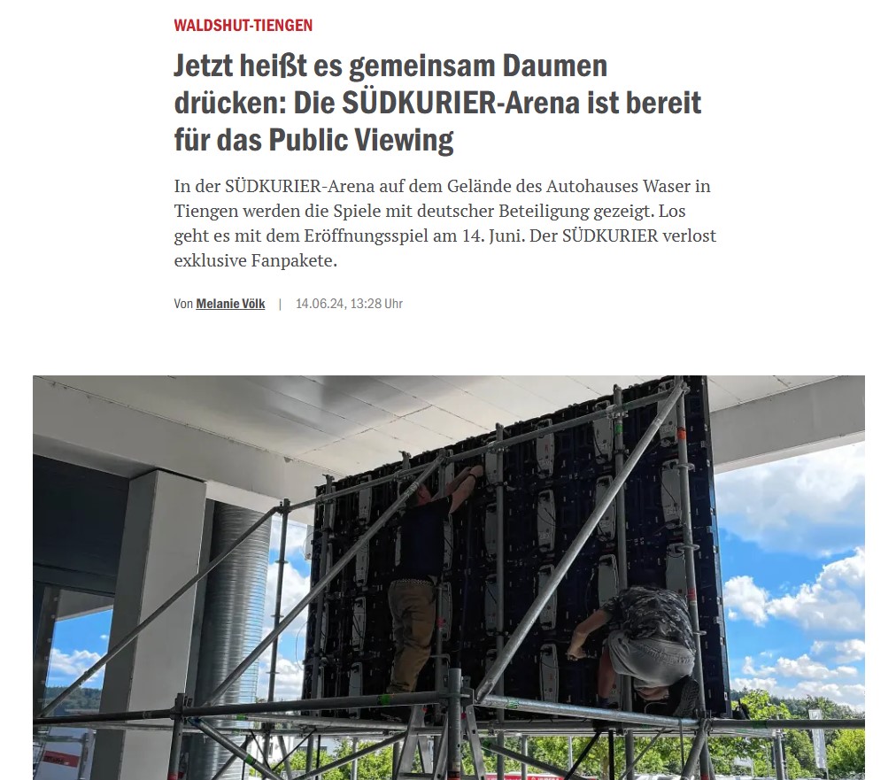 Menschen montieren eine große LED-Leinwand auf einem Gerüst im Freien.