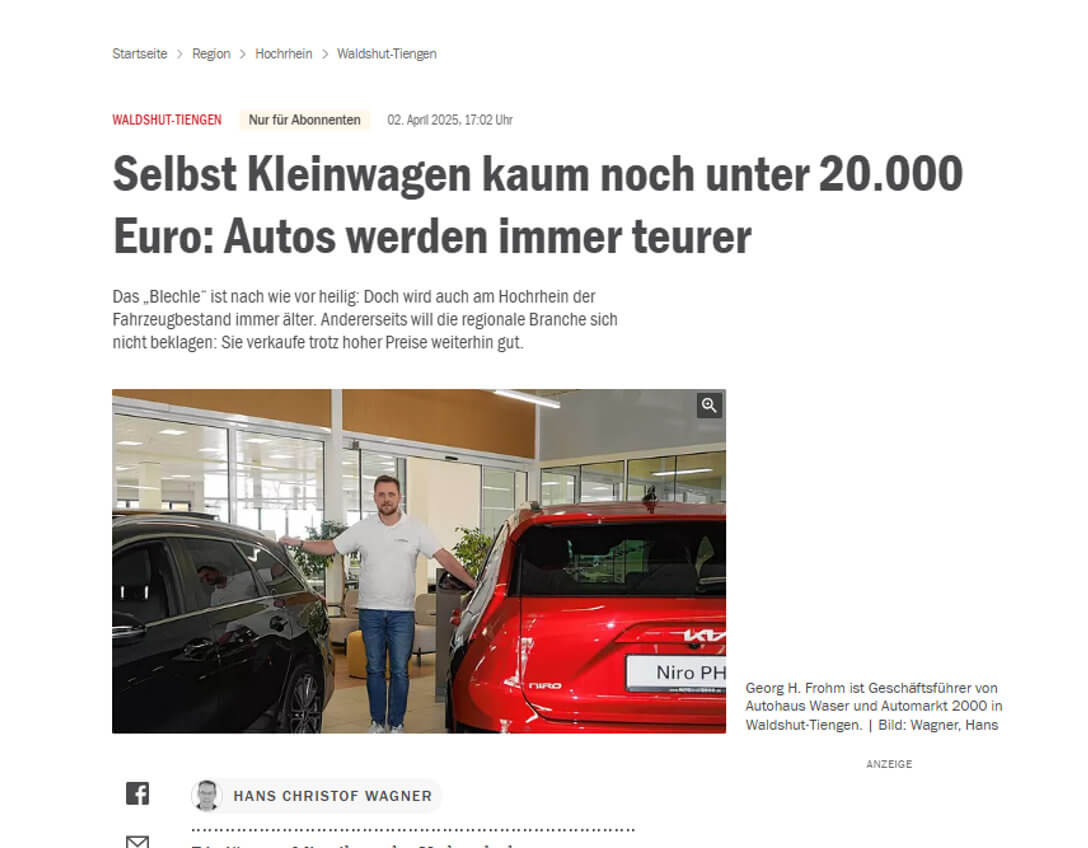 Ein Mann steht zwischen einem schwarzen und einem roten Auto in einem Autohaus.