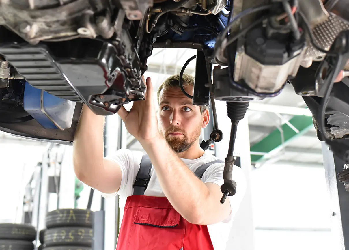 Ein Mechaniker repariert den Unterboden eines Autos in einer Werkstatt.
