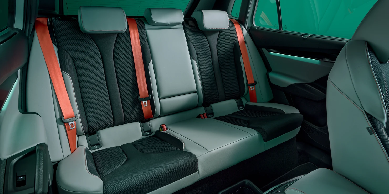 Rückbank eines Autos mit roten Sicherheitsgurten und schwarzem Polster.