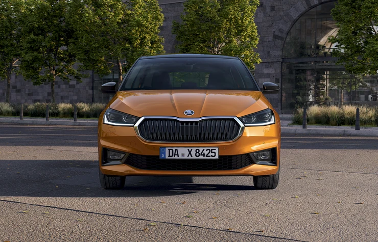 Fabia_small_1 Ein orangefarbener Škoda Fabia steht auf einer Straße.