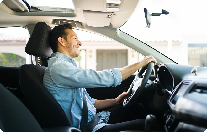 Hol- und Bringservice Ein Mann fährt lächelnd ein Auto.