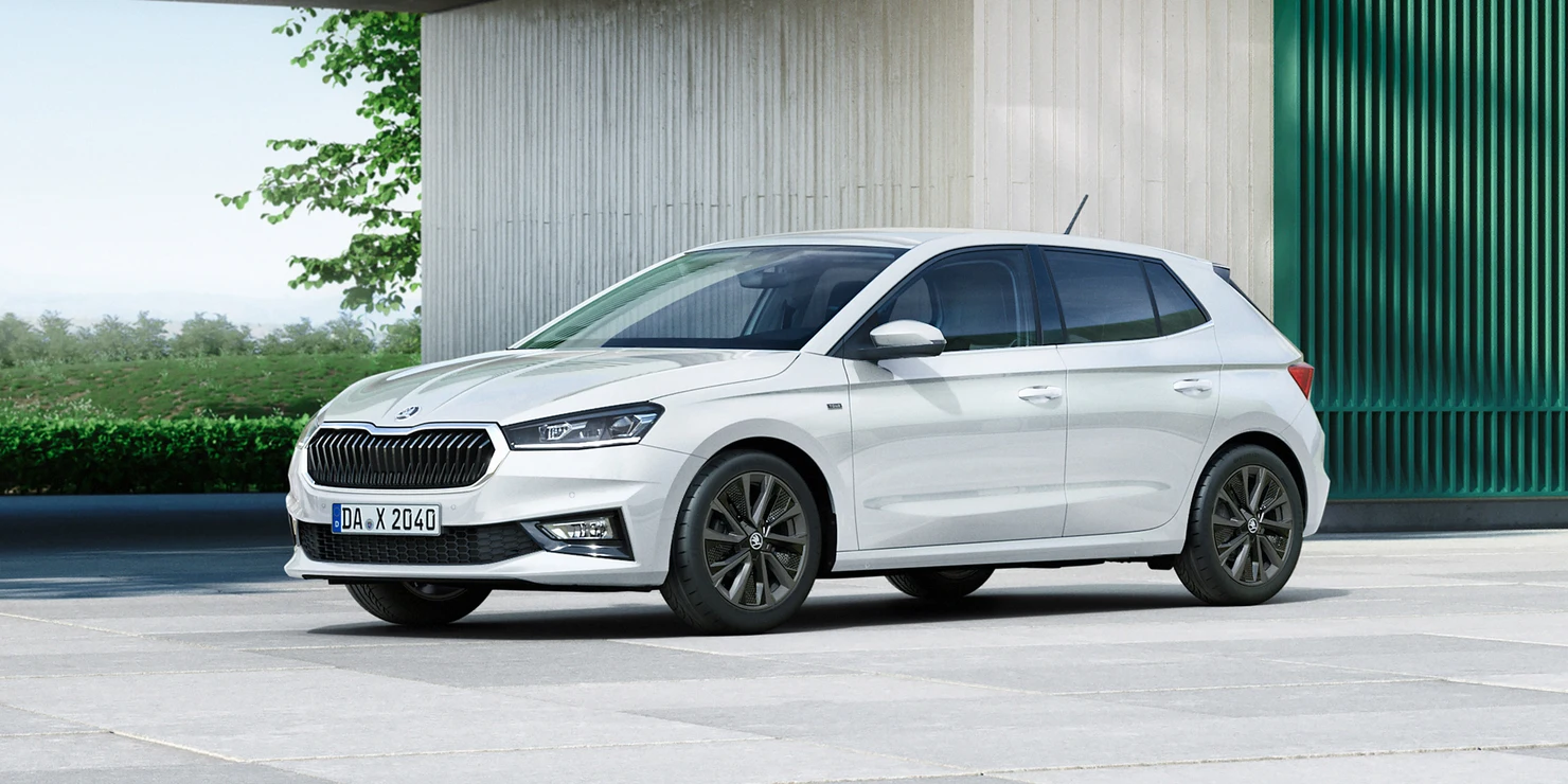 Ein weißer Škoda Fabia Tour steht vor einem modernen Gebäude.