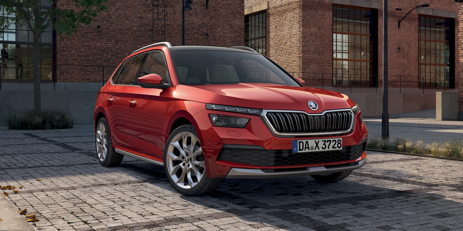 Ein roter Škoda Kamiq steht auf einem gepflasterten Platz vor einem Backsteingebäude.