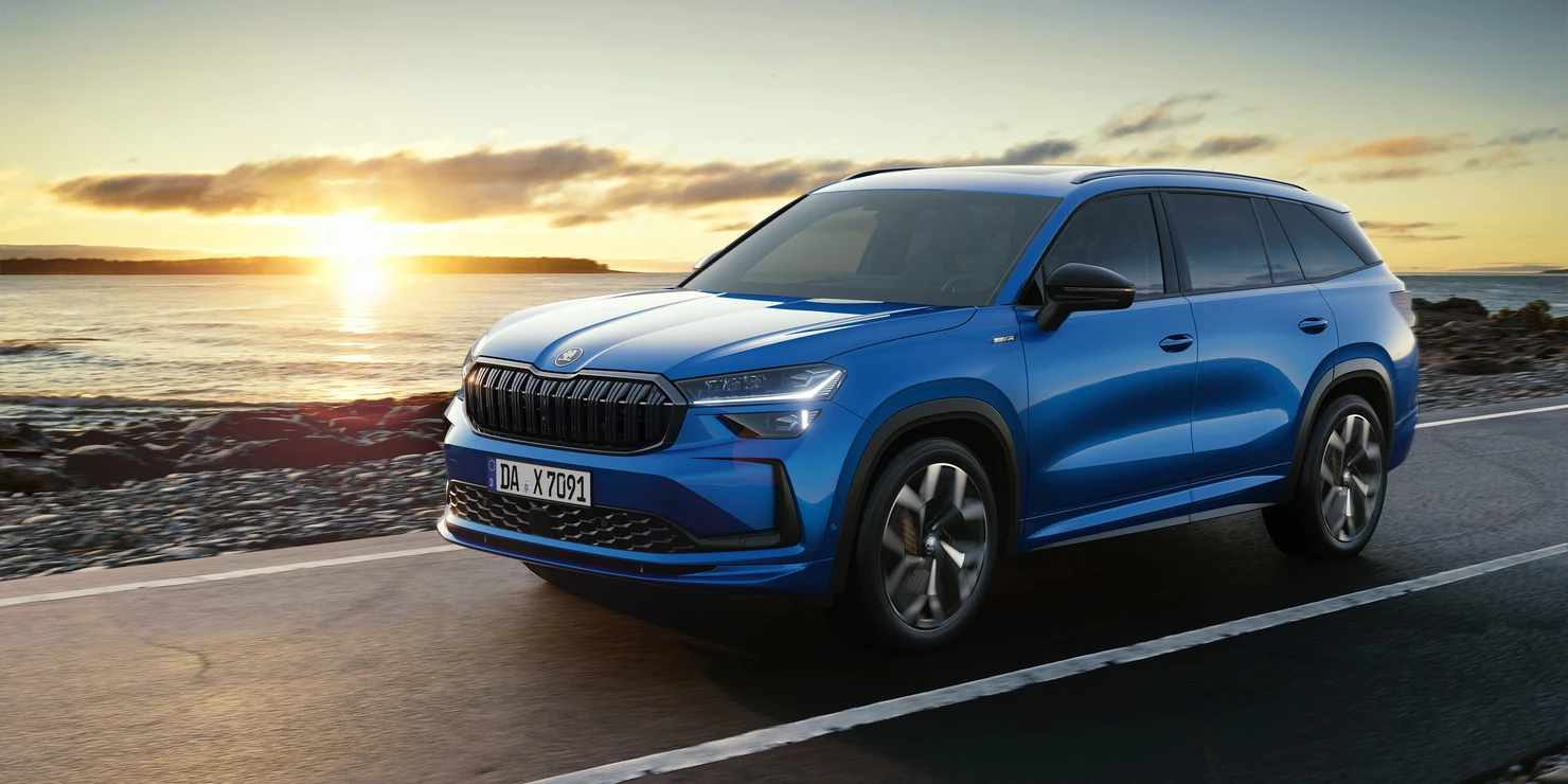 Blauer Škoda Kodiaq Sportline fährt bei Sonnenuntergang an der Küste entlang.