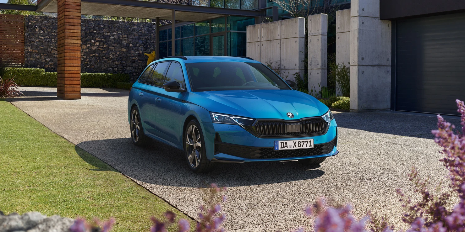 Ein blauer Škoda Octavia Combi Sportline steht auf einer Einfahrt vor einem modernen Gebäude.