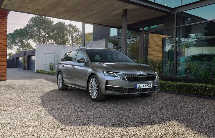 Ein silberner Skoda Octavia Combi parkt vor einem modernen Gebäude.