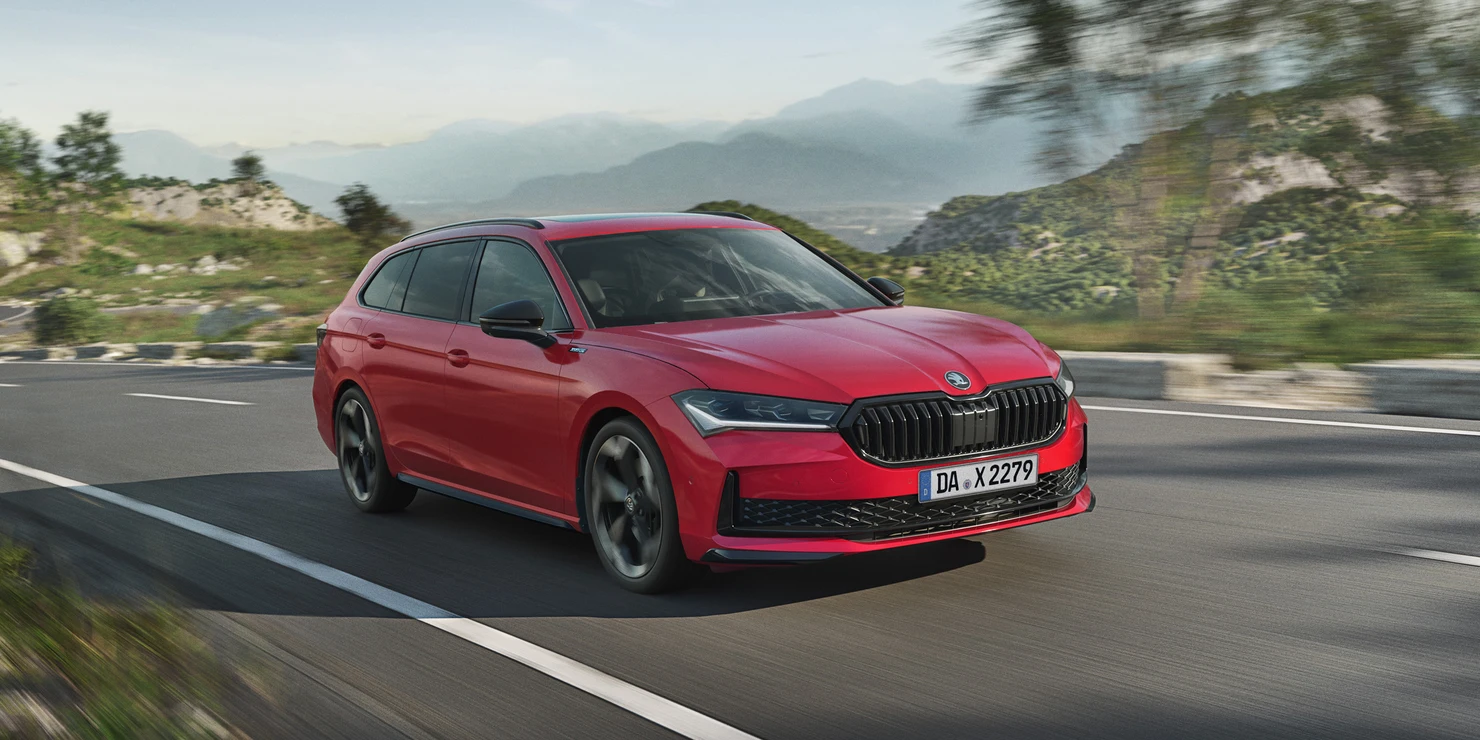 Ein roter Škoda Superb Combi Sportline fährt auf einer Landstraße.