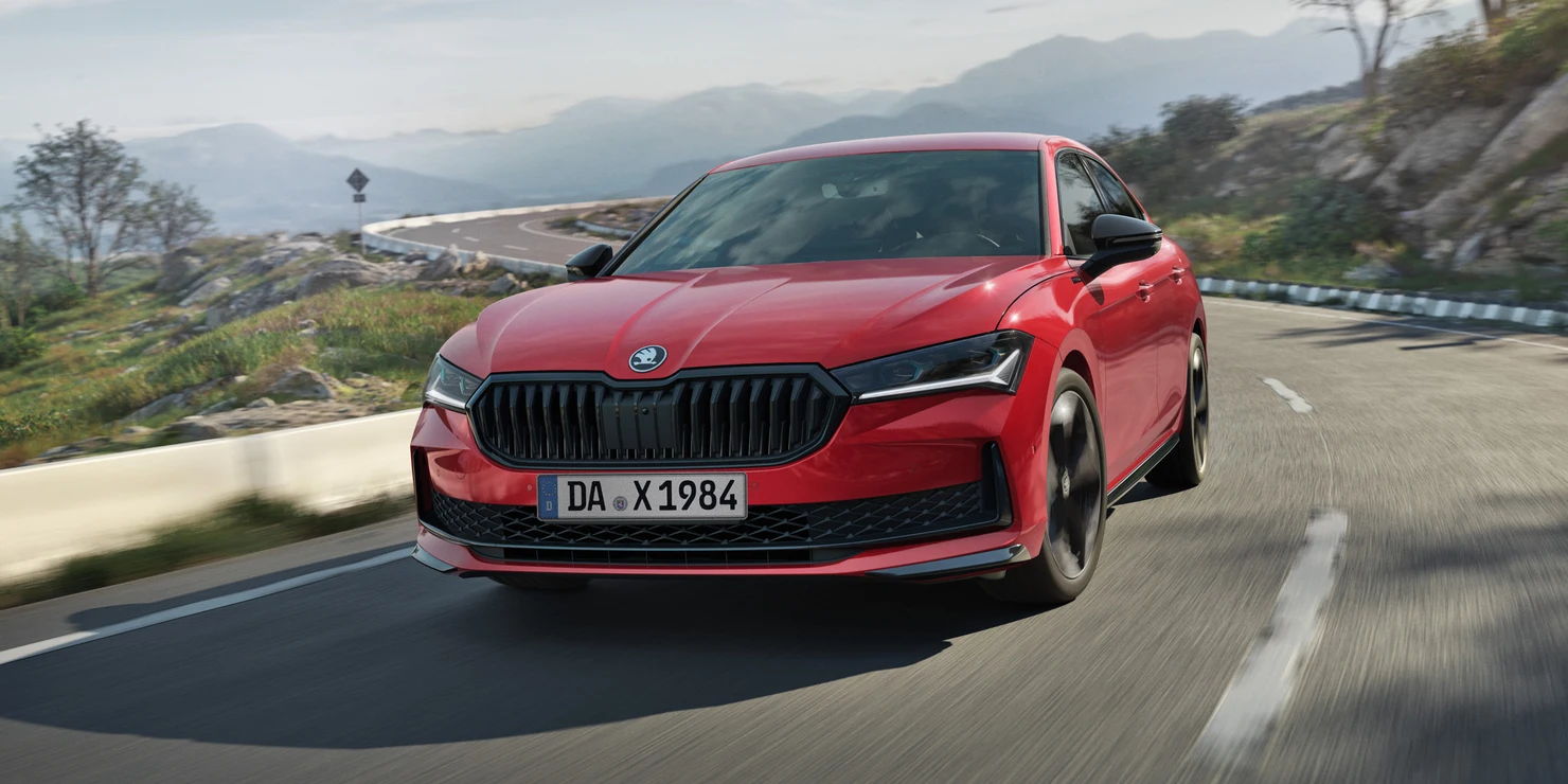Ein roter Škoda Superb Sportline fährt auf einer kurvigen Straße.