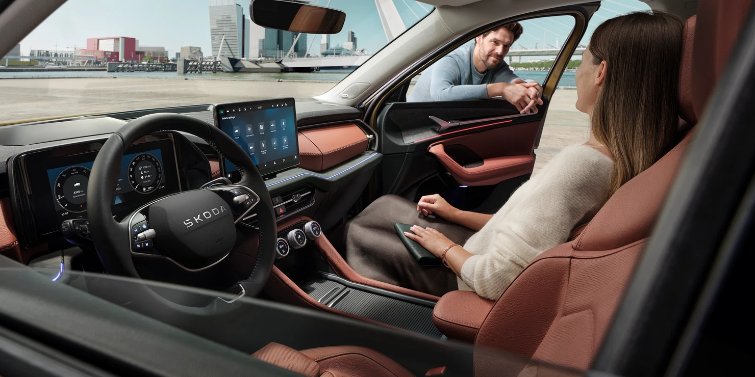 Innenansicht eines Škoda Kodiaq mit einer Frau auf dem Beifahrersitz und einem Mann, der sich ins Auto lehnt.