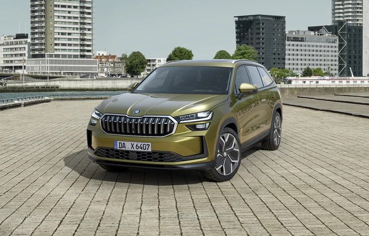 Kodiaq-gg_bp1920_1 Ein grüner Škoda Kodiaq steht auf einem gepflasterten Platz vor modernen Gebäuden.
