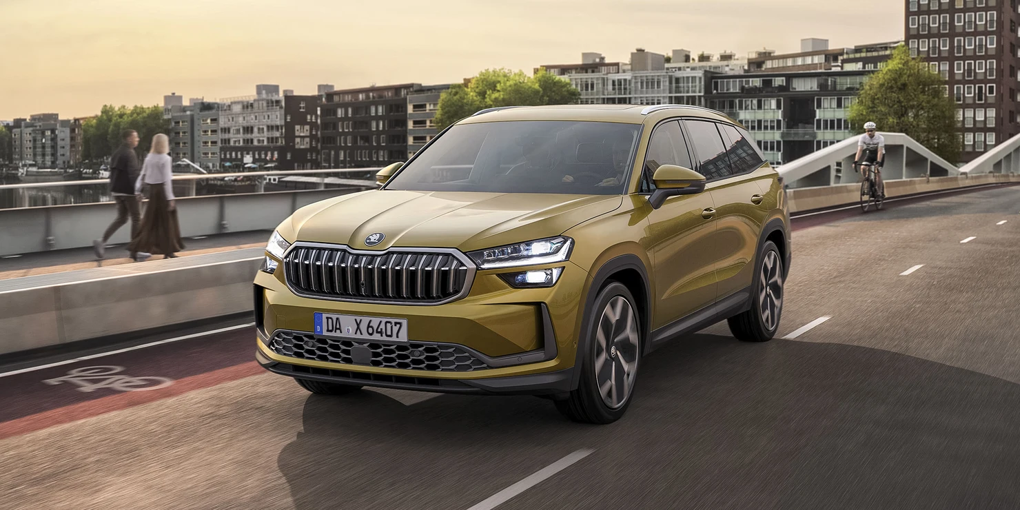 Ein goldener Škoda Kodiaq fährt auf einer städtischen Straße.