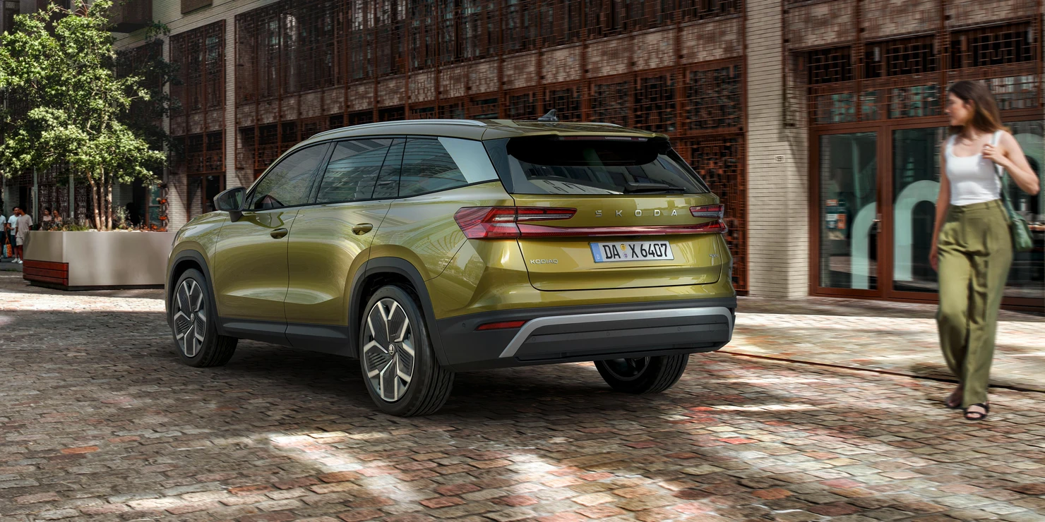 Grüner Škoda Kodiaq auf einer gepflasterten Straße in einer städtischen Umgebung.