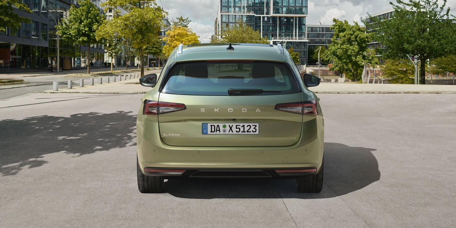 Rückansicht eines grünen Škoda Superb Kombi mit Kennzeichen auf einer städtischen Straße.