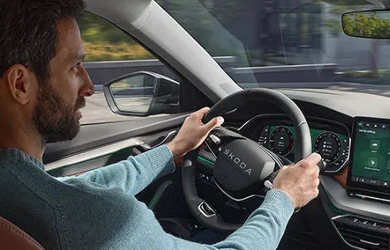 care-connect Ein Mann fährt einen Škoda und hält das Lenkrad fest.