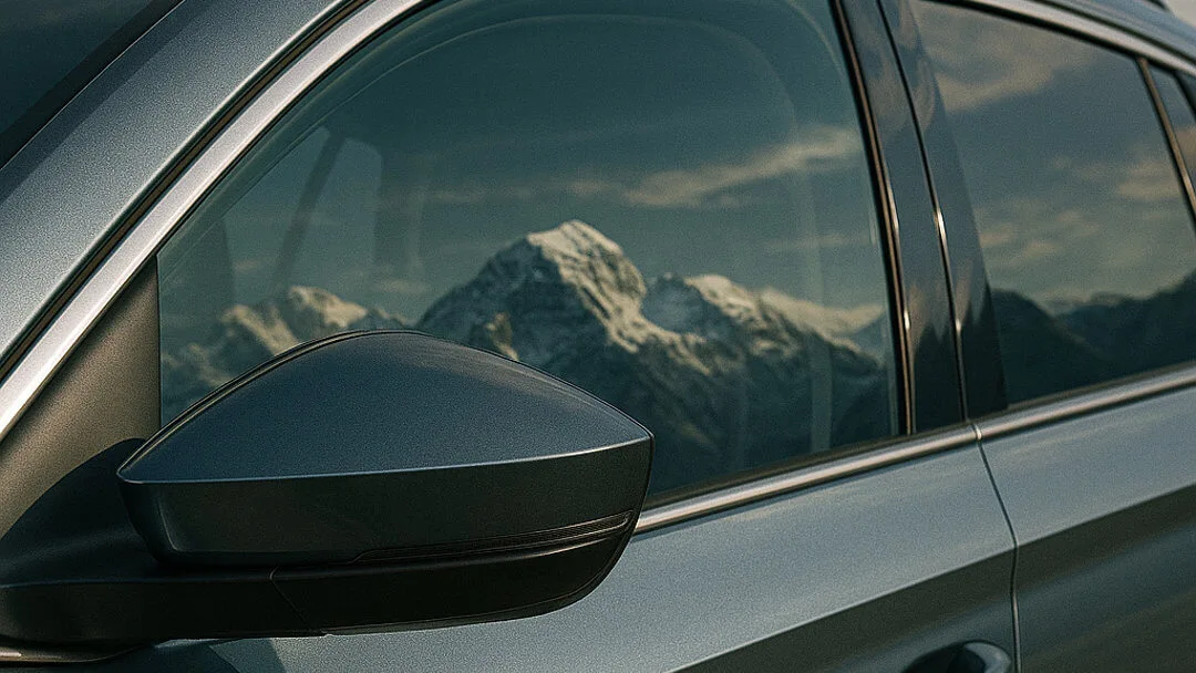 export-schweiz-text-bild-teaser Nahaufnahme eines Autospiegels mit Schweizer Berglandschaft im Hintergrund.