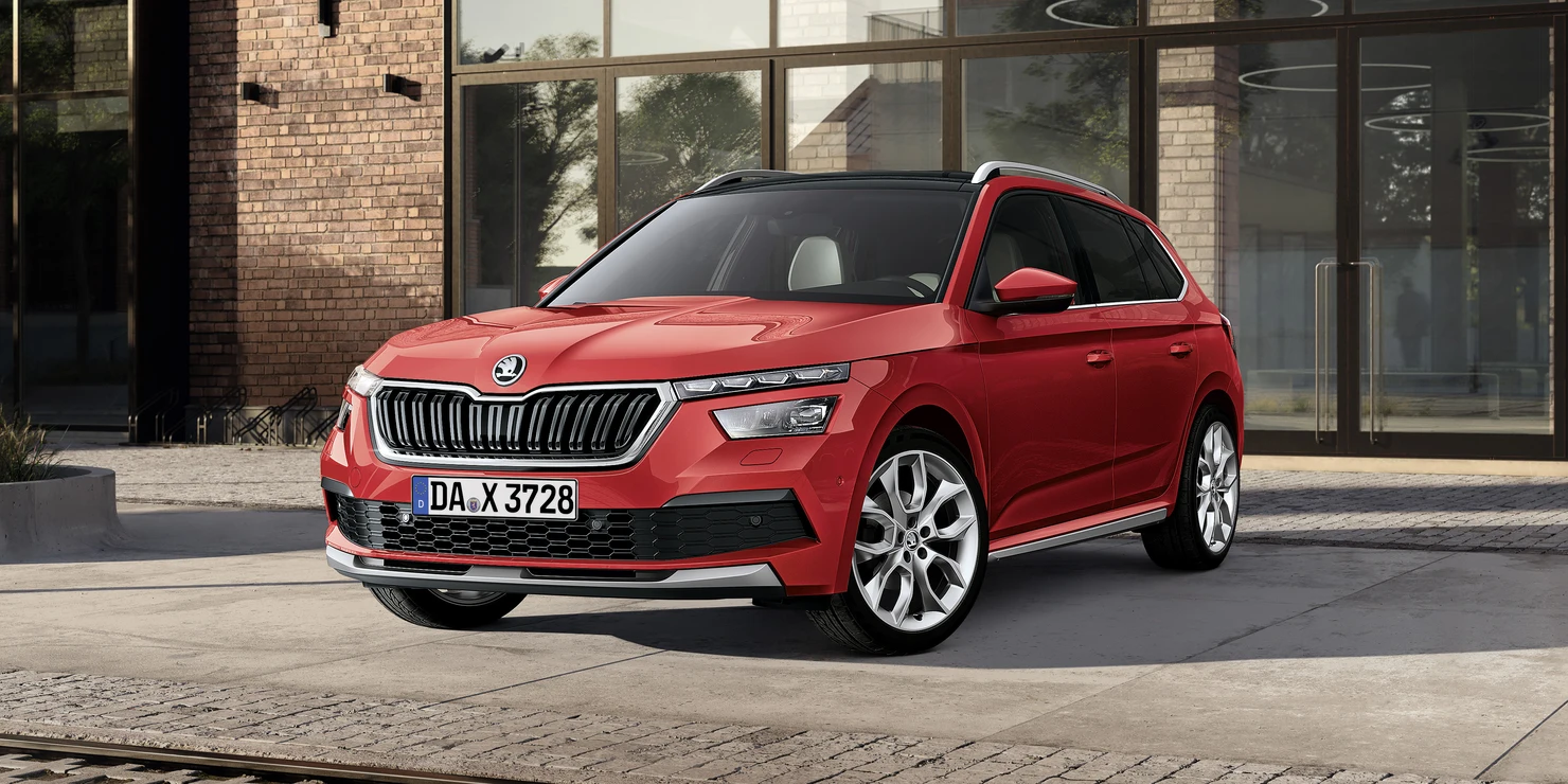 Rotes Škoda Kamiq Auto vor einem modernen Gebäude.