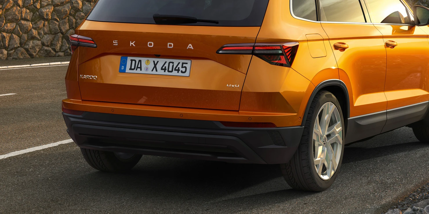 Ein orangefarbener Škoda Karoq 2025 von hinten auf einer Straße.