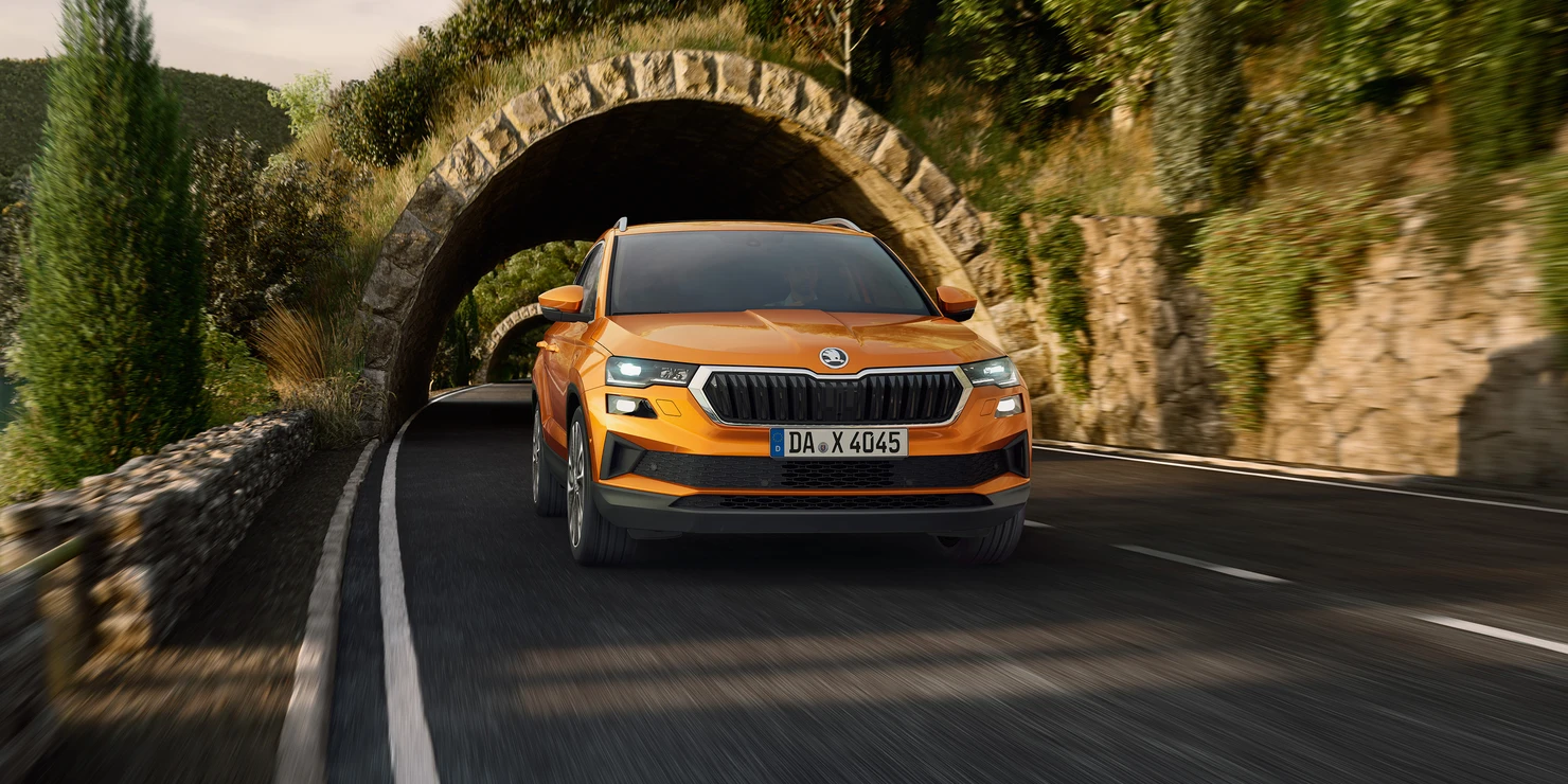 Ein orangefarbener Škoda Karoq fährt durch einen steinernen Tunnel.