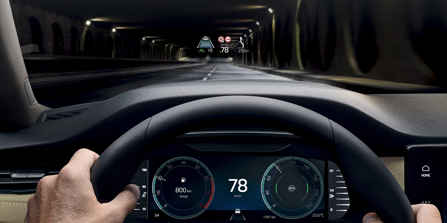 Ein Fahrer hält das Lenkrad eines Skoda Octavia, während ein Head-up-Display Informationen zur Geschwindigkeit und Navigation projiziert.