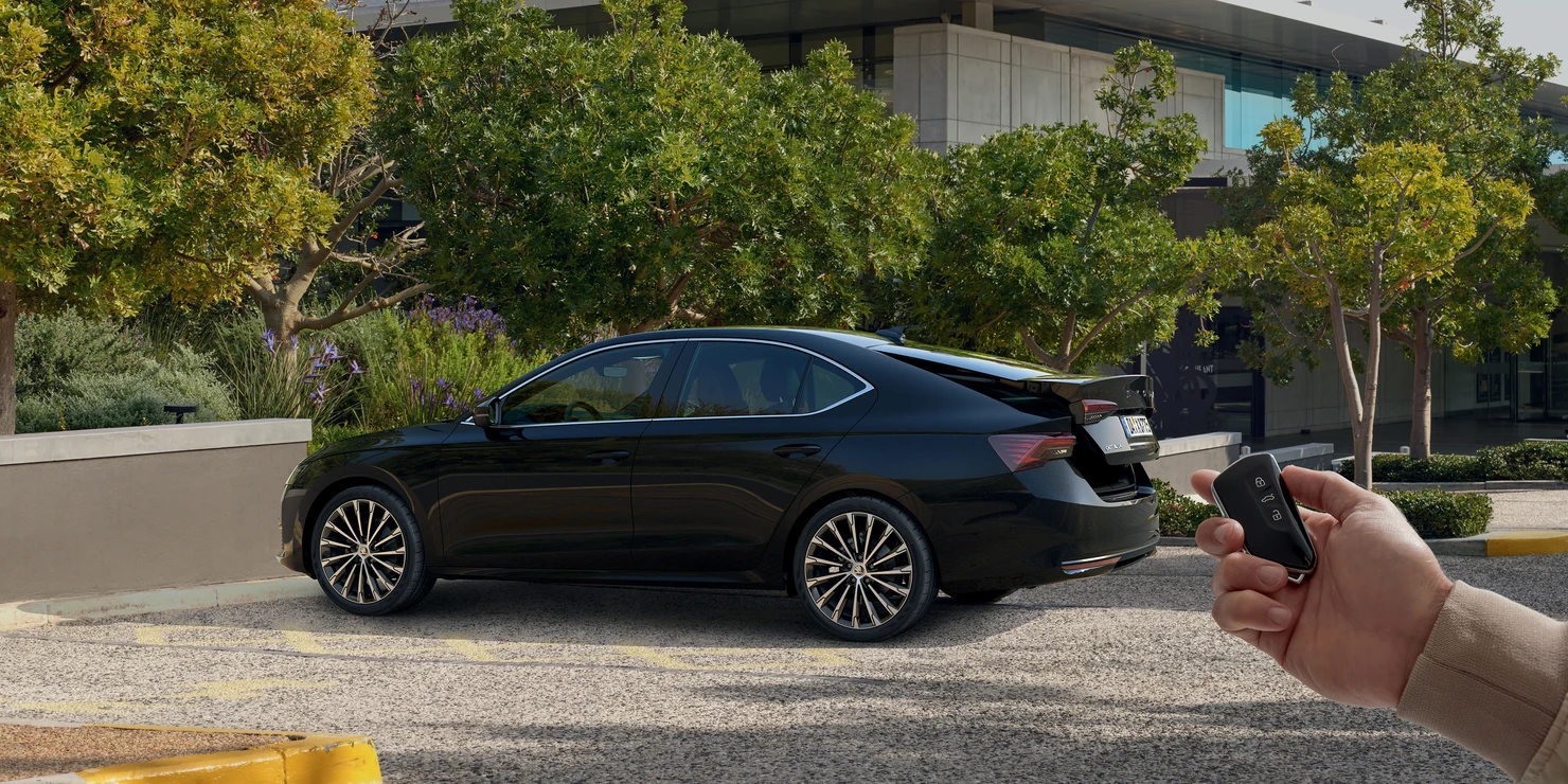 Ein schwarzer Skoda Octavia 2025 steht auf einem Parkplatz, während eine Hand einen Autoschlüssel hält.