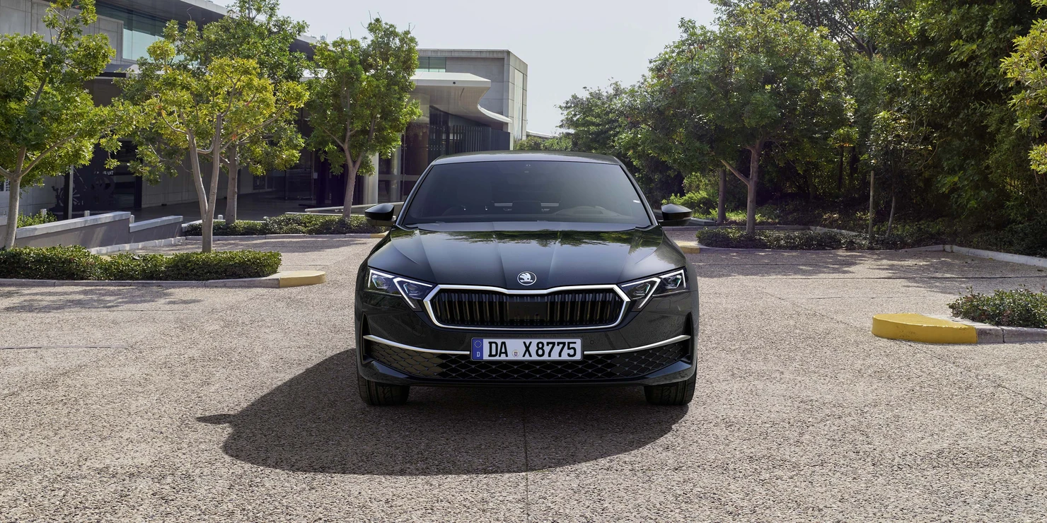Ein schwarzer Škoda Octavia 2025 steht auf einem Parkplatz vor einem modernen Gebäude.