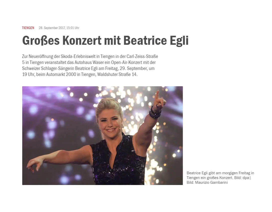 Eine Frau auf einer Bühne lächelt und hebt einen Arm in die Luft.