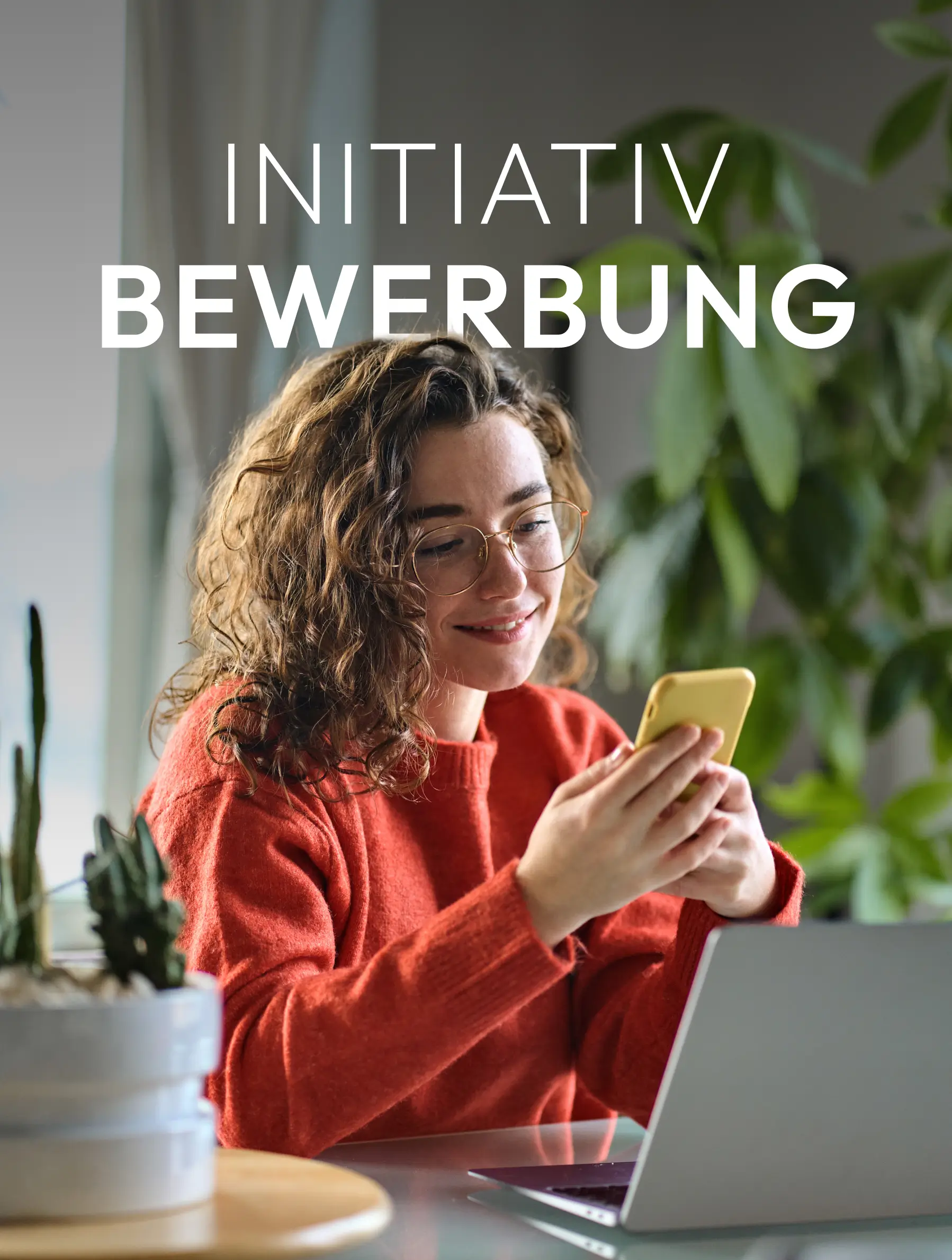 Initiativ-Bewerbung Person in rotem Pullover schaut lächelnd auf ein Smartphone vor einem Laptop.