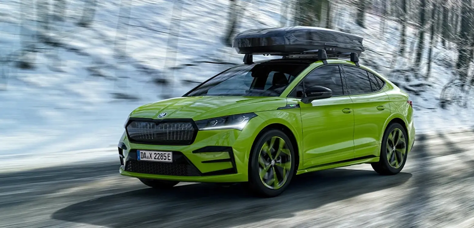 Grüner Škoda Enyaq fährt auf verschneiter Straße.