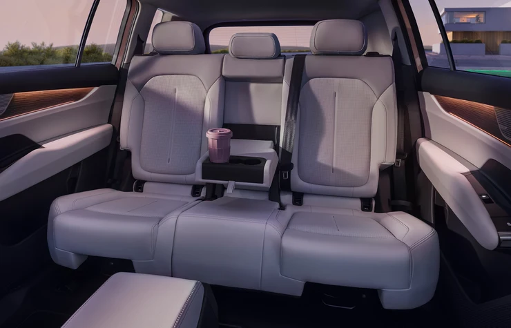 Rückbank eines Autos mit heller Innenausstattung und einem Becherhalter.