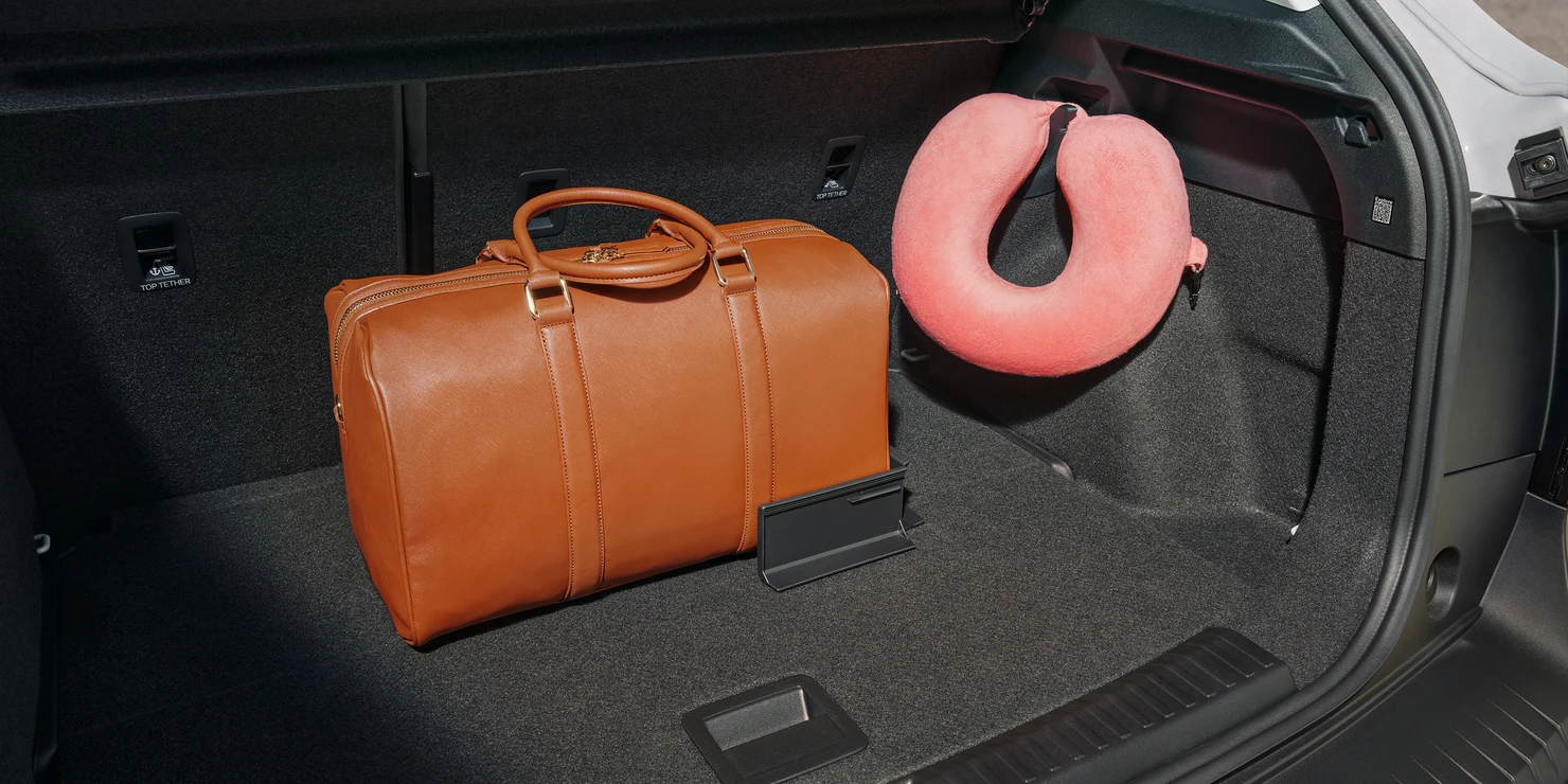 Brauner Lederkoffer und Nackenkissen im Kofferraum eines Autos.