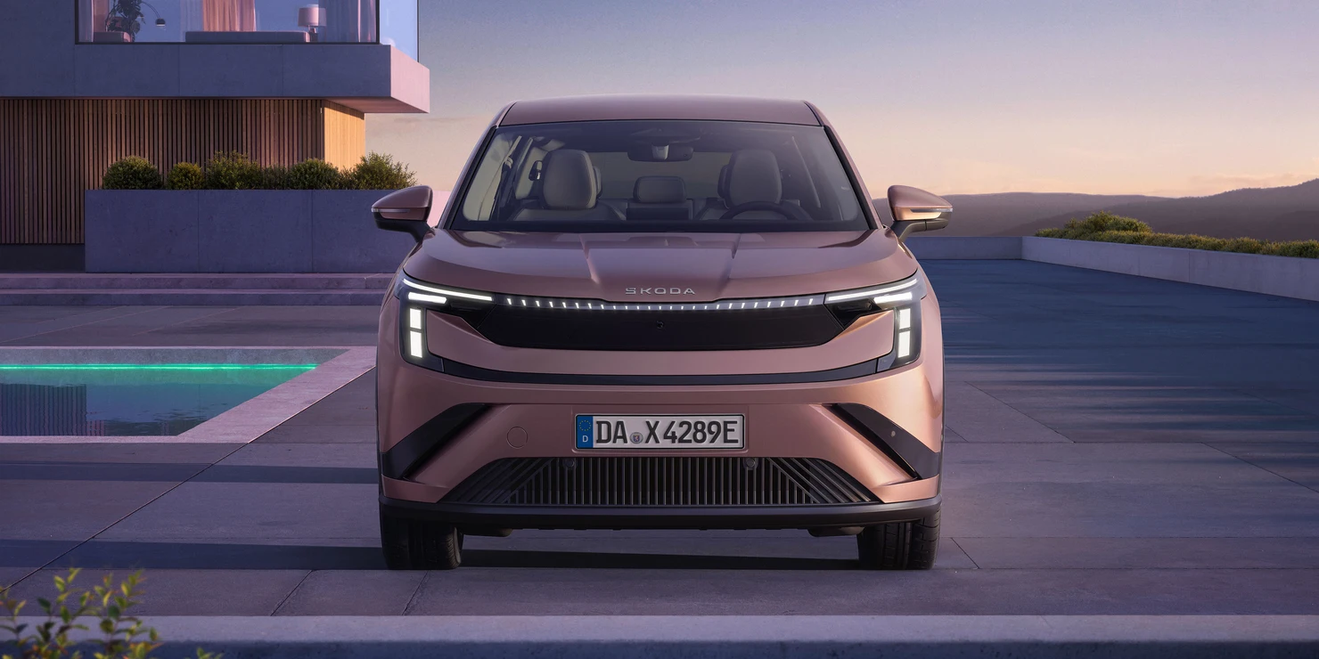 Ein rosafarbener Škoda Peaq SUV steht vor einem modernen Gebäude.